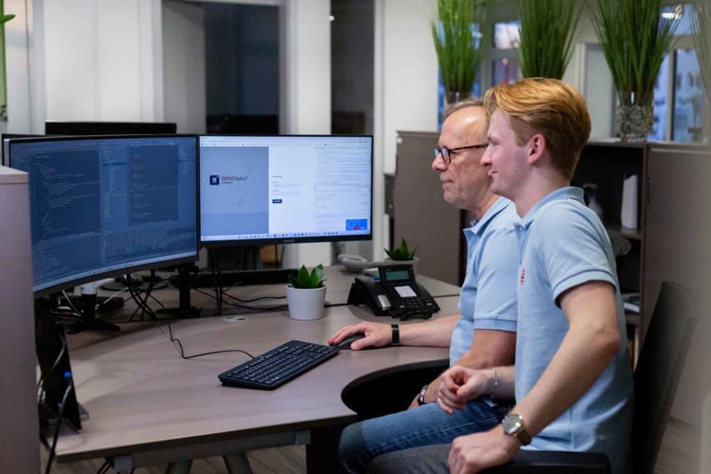 Mitarbeiter des Software Service Stadermann lernen von einander am Computer